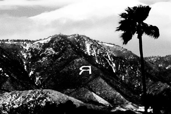 A black and white photograph of the mountains above Redlands with the letter R on the side of a mountain